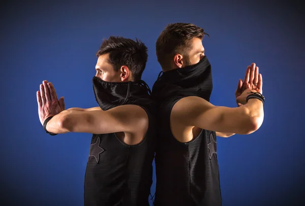 Deux danseurs masculins posant en costumes ninja sur fond bleu — Photo