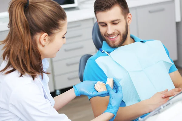 Dentista explicando ao paciente masculino como escovar os dentes . — Fotografia de Stock