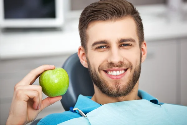 Porträtt av glad tålmodig i dental stol med grönt äpple. — Stockfoto