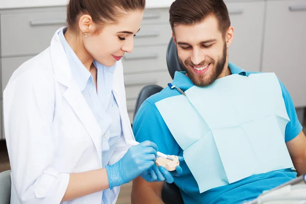 Стоматолог пояснює пацієнту чоловічої статі, як чистити зуби . — стокове фото