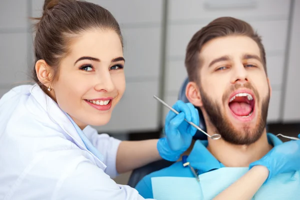 Young man getting his teeth checked by a dentist. — Stock Photo, Image