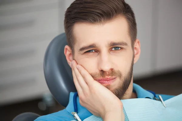 Retrato de homem jovem com dor de dente sentado no cha de um dentista — Fotografia de Stock