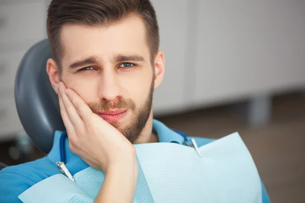 Portret van een jonge man met tand pijn zitten in van een tandarts cha — Stockfoto