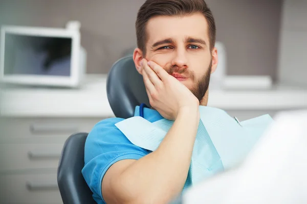 Portret van een jonge man met tand pijn zitten in van een tandarts cha — Stockfoto