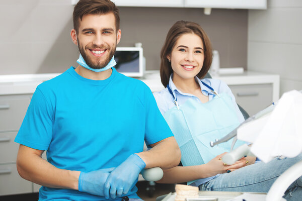 Portrait of a male dentist and young happy  female patient.