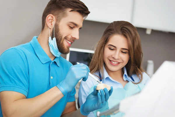Dentista explicando a la paciente cómo cepillarse los dientes . —  Fotos de Stock