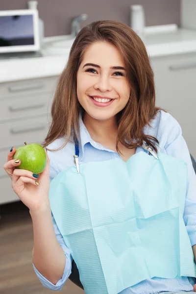 Retrato de paciente feliz em cadeira dental com maçã verde . — Fotografia de Stock