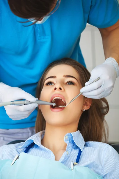 Mujer joven que se hace revisar los dientes por un dentista . —  Fotos de Stock