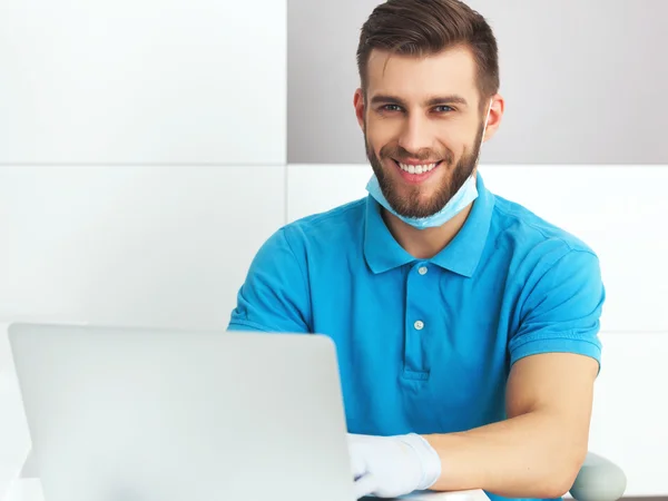 Jovem dentista do sexo masculino trabalhando com notebook . — Fotografia de Stock