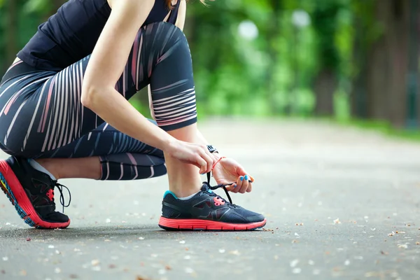 Nahaufnahme junge Frau bindet ihre Schnürsenkel vor einem Lauf. — Stockfoto