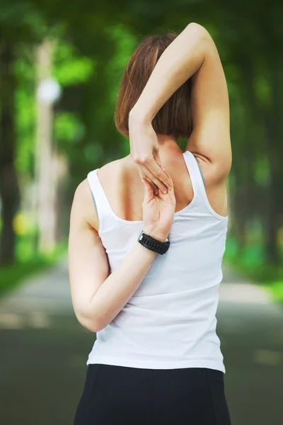 Junge Frau dehnt sich im Park. — Stockfoto