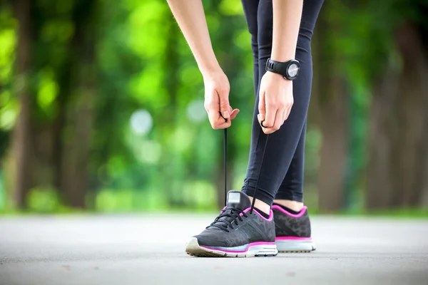 Junge Frau bindet ihre Schnürsenkel vor einem Lauf. — Stockfoto