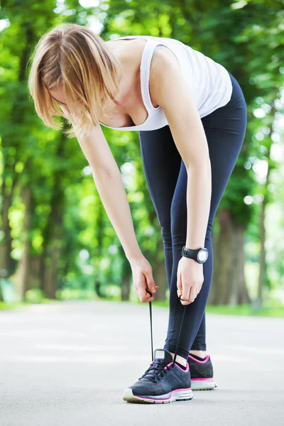 Junge Frau bindet ihre Schnürsenkel vor einem Lauf. — Stockfoto