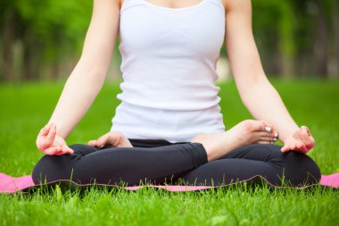 Parkta yoga yapan genç kadın..