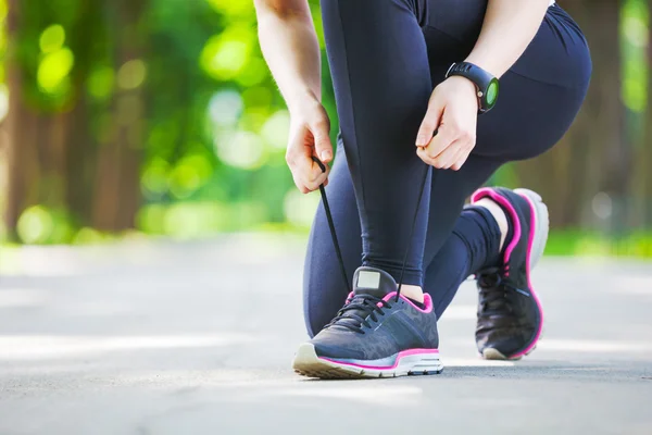 Junge Frau bindet ihre Schnürsenkel vor einem Lauf. — Stockfoto