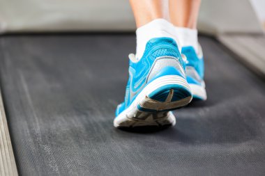 spor salonunda koşu bandı üzerinde çalışan kadın.
