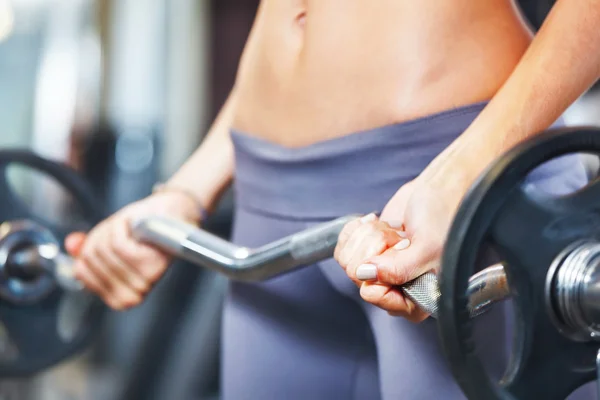 Jeune femme faisant de l'exercice avec haltère en salle de gym. — Photo