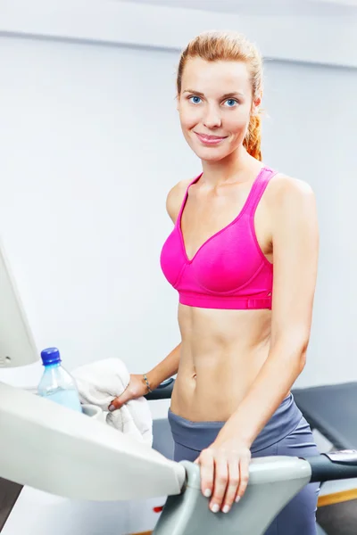 Ung kvinna gör konditionsträningen på löpband i ett gym. — Stockfoto