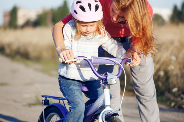 Rödhårig tjej i hjälm lärande ridning cykel. — Stockfoto