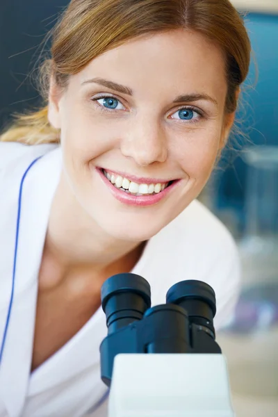 Porträt der schönen jungen Ärztin unter dem Mikroskop. — Stockfoto