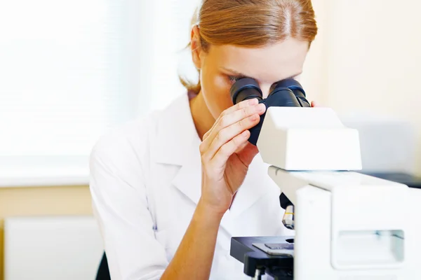 Woman working with a microscope. Royalty Free Stock Photos