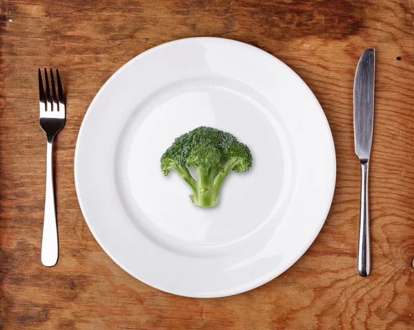 Kniv, gaffel och plattan med broccoli på träbord. — Stockfoto