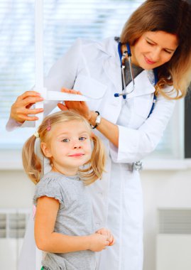 Doktor bir şirin Kızıl saçlı kız yüksekliğini ölçme.