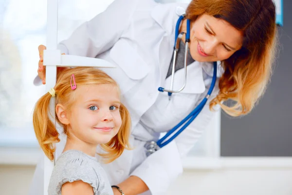 Doktor bir şirin Kızıl saçlı kız yüksekliğini ölçme.