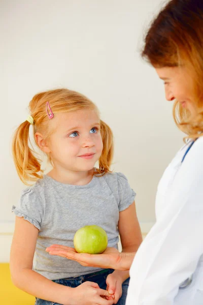 Arzt gibt kleinen Patienten grünen Apfel. — Stockfoto