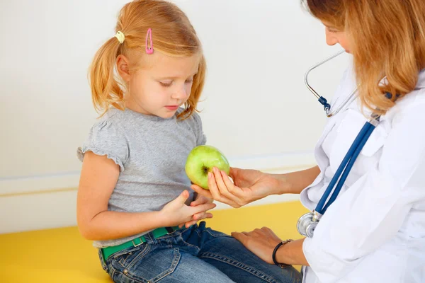 Arzt gibt kleinen Patienten grünen Apfel. — Stockfoto