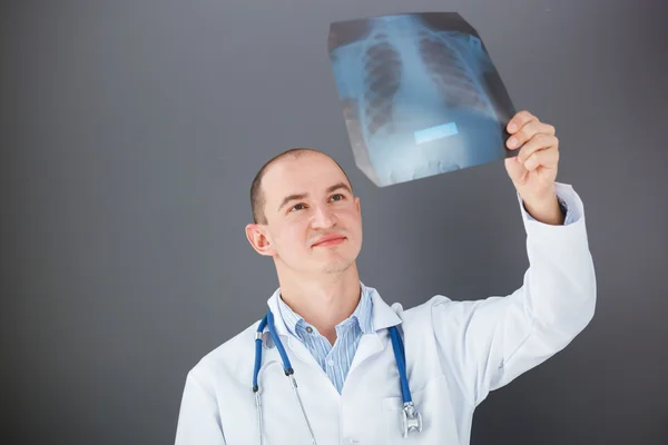 Junger Arzt schaut sich Röntgenbild an. — Stockfoto