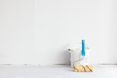 Beyaz üzerine rulo fırça ile boya kovası.