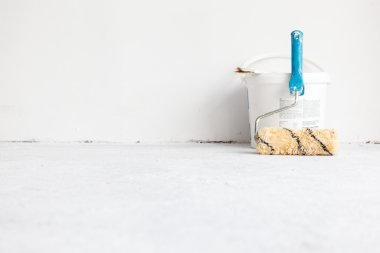 Beyaz üzerine rulo fırça ile boya kovası.