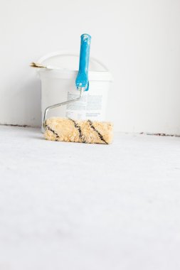 Beyaz üzerine rulo fırça ile boya kovası.