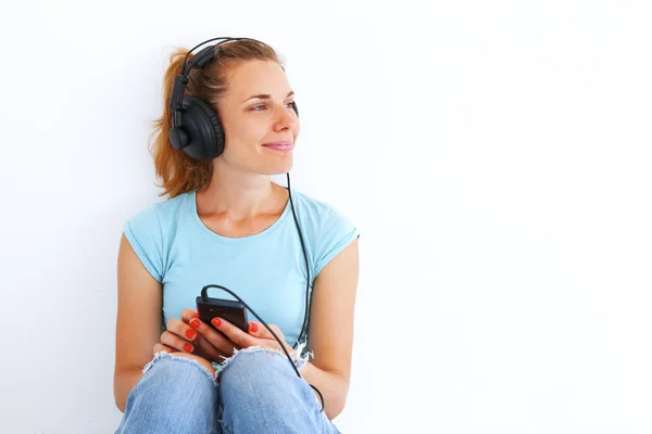 Ung kvinna lyssnar musik med hörlurar. — Stockfoto
