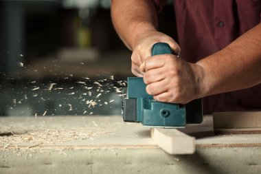 Carpenter working with electric planer. clipart