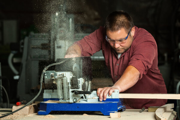 Professional carpenter working with sawing machine.