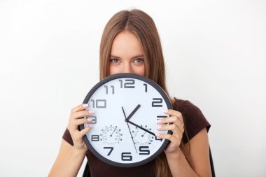 Beyaz arka plan üzerinde büyük duvar tutan genç kadın saatler.