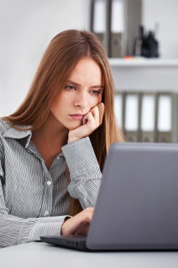 Sıkılmış genç iş kadını laptop ile çalışma.