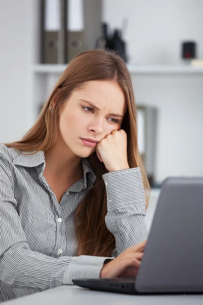 Entediada jovem mulher de negócios trabalhando com laptop . Imagens Royalty-Free