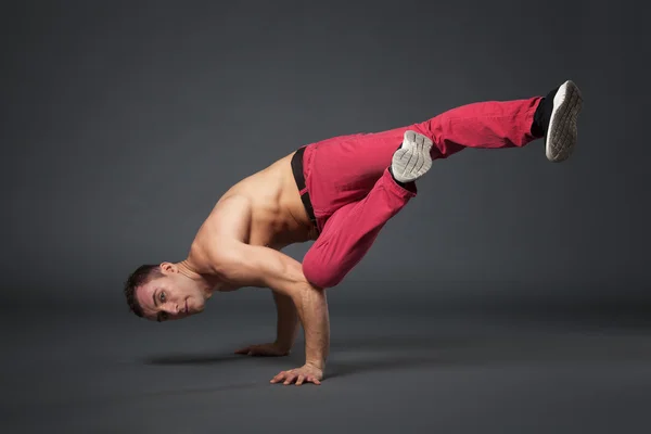 Young male professional dancer B-boying on gray background. — Stock Photo, Image