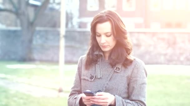 Atractiva mujer de negocios usando su teléfono inteligente caminando al aire libre — Vídeos de Stock