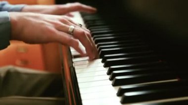 Genç adam kamera hareketi ile odak değiştirmenin hızlı bir piyano müzik üzerinde çalış 