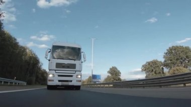 Kargo kamyonu ve kargo karavanı bir otoyolda gidiyor. Beyaz Kamyon sabahın erken saatlerinde mal teslim ediyor. Çok düşük açılı bir araç. Yakın çekim sırasında..