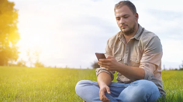 Genç adam açık havada Smartphone kullanarak — Stok fotoğraf