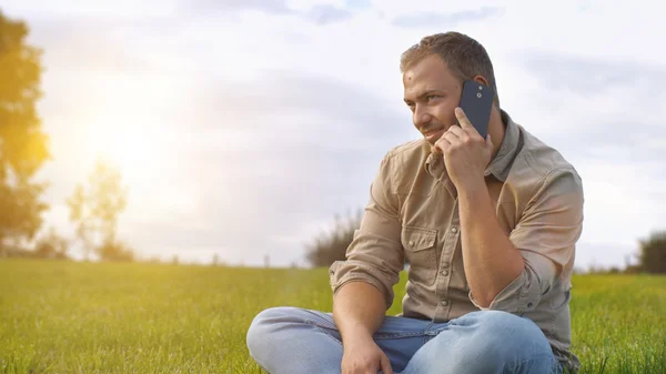 A szabadban a smartphone beszélő fiatalember — Stock Fotó