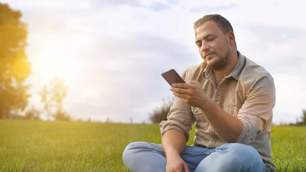 Genç adam açık havada Smartphone kullanarak — Stok fotoğraf