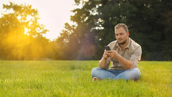 Genç adam açık havada Smartphone kullanarak — Stok fotoğraf