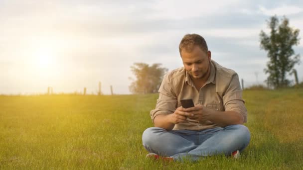 Hombre joven utilizando el teléfono inteligente al aire libre — Vídeos de Stock