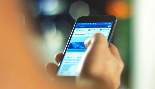 Hombre utiliza aplicación de Facebook en el teléfono inteligente —  Fotos de Stock